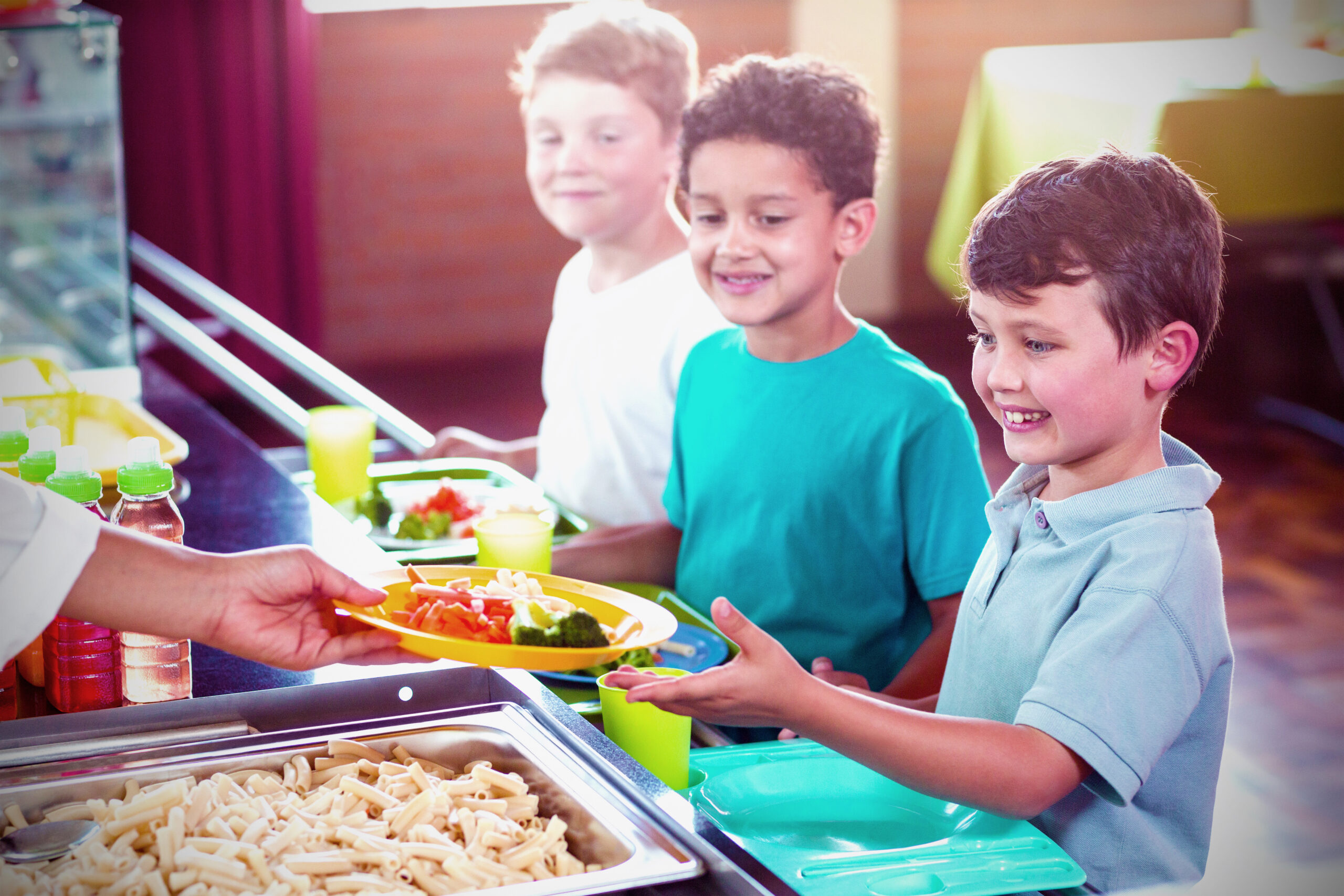 children, three boys, in school cafeteria getting served lunch