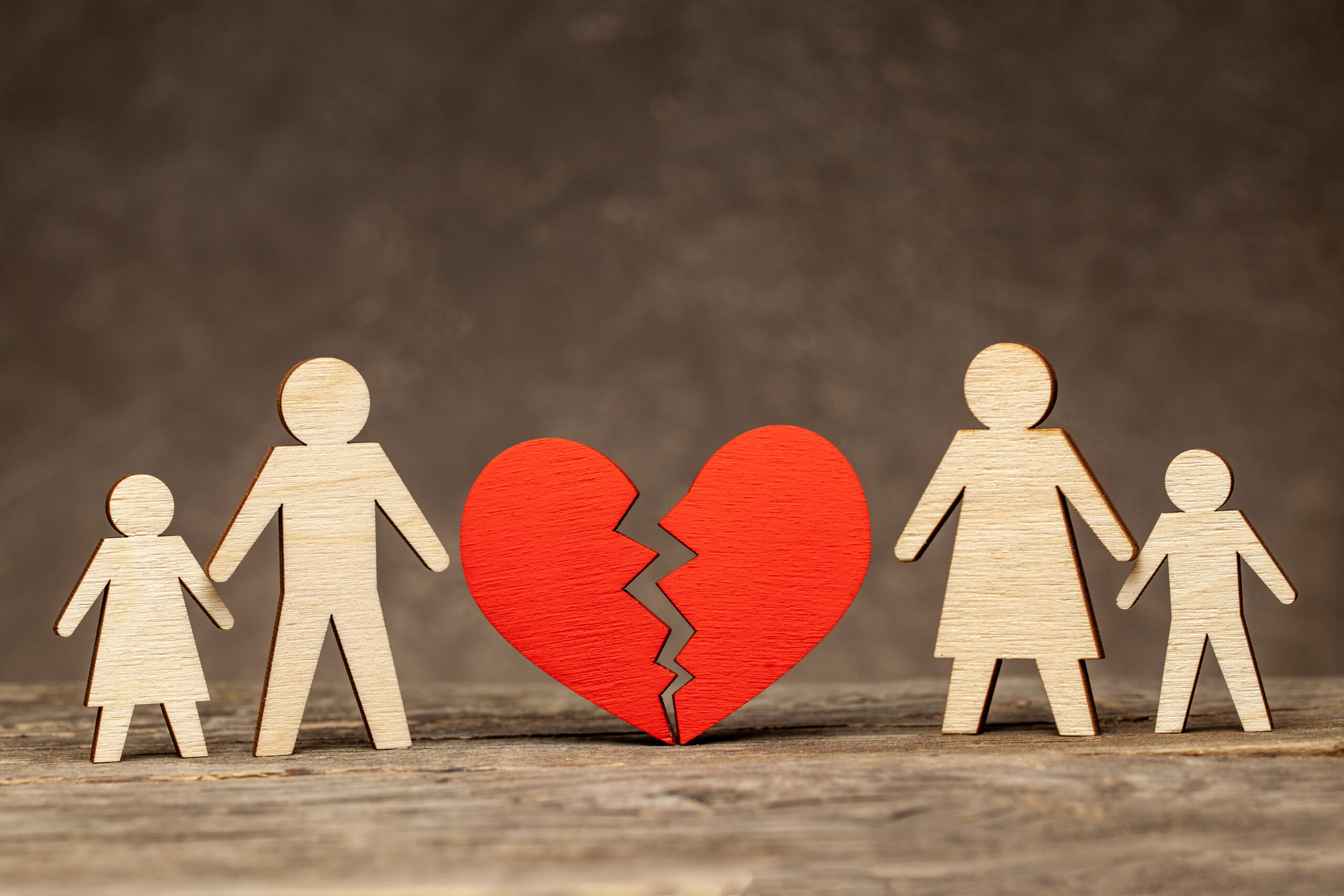 Divorce in a family with children wooden figures of family and broken heart