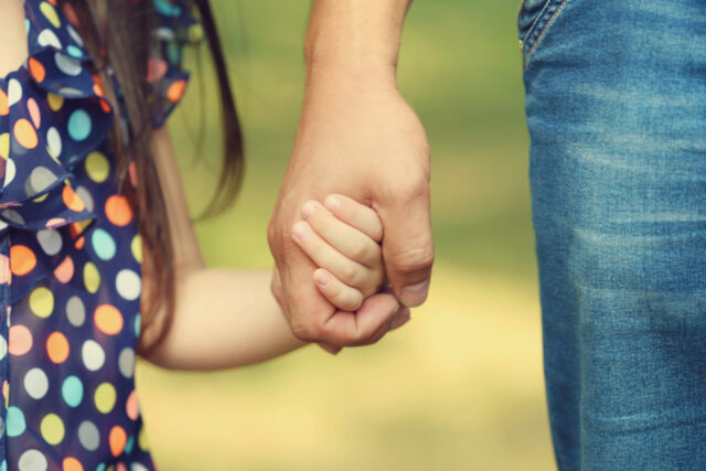 Father's hand lead his child daughter outdoors, trust family
