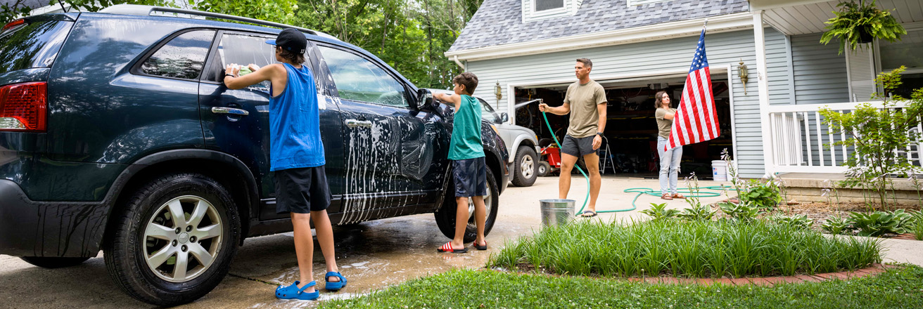 Air Force service member washes his vehicles with his sons in the driveway