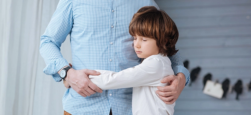 boy closing his eyes and hugging his father