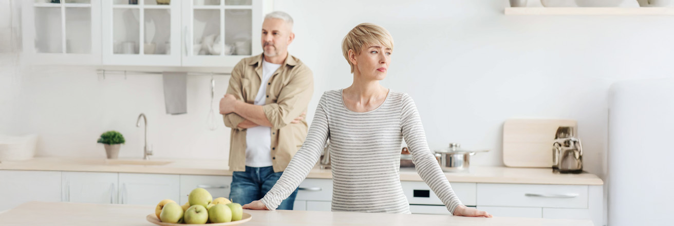 older couple standing in kitchen looking opposite directions