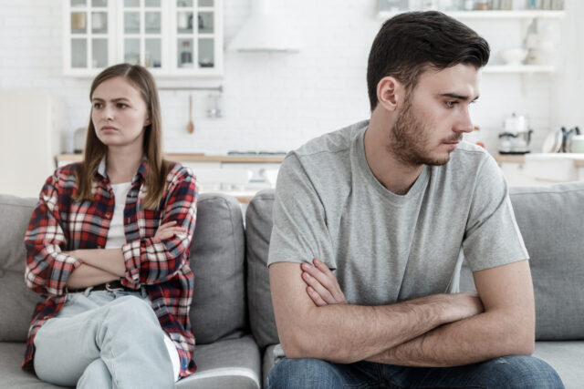 man and woman spending time in living room, not eager to talk in result of misunderstanding or other relationship problems