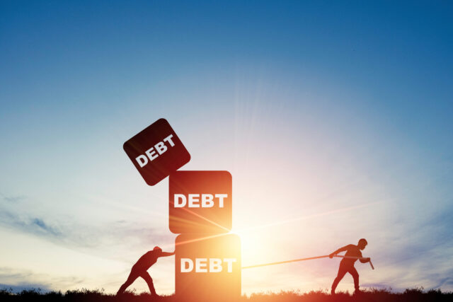 Silhouette of two men pushing and pulling debt weight boxes stacking for debt and financial freedom concept.