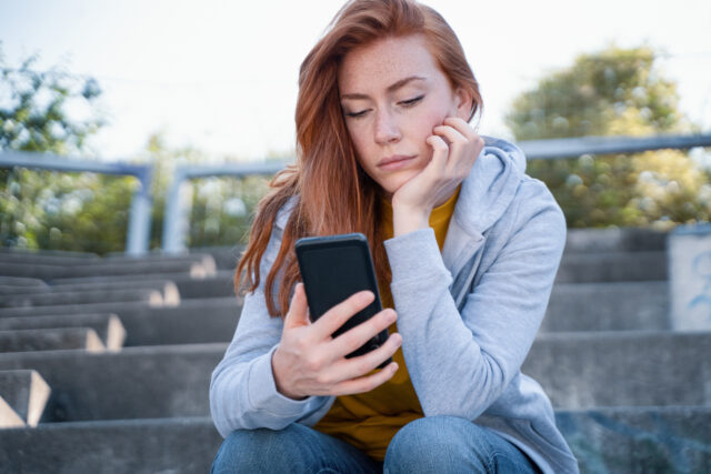 Sad girl watching smartphone and feeling bad