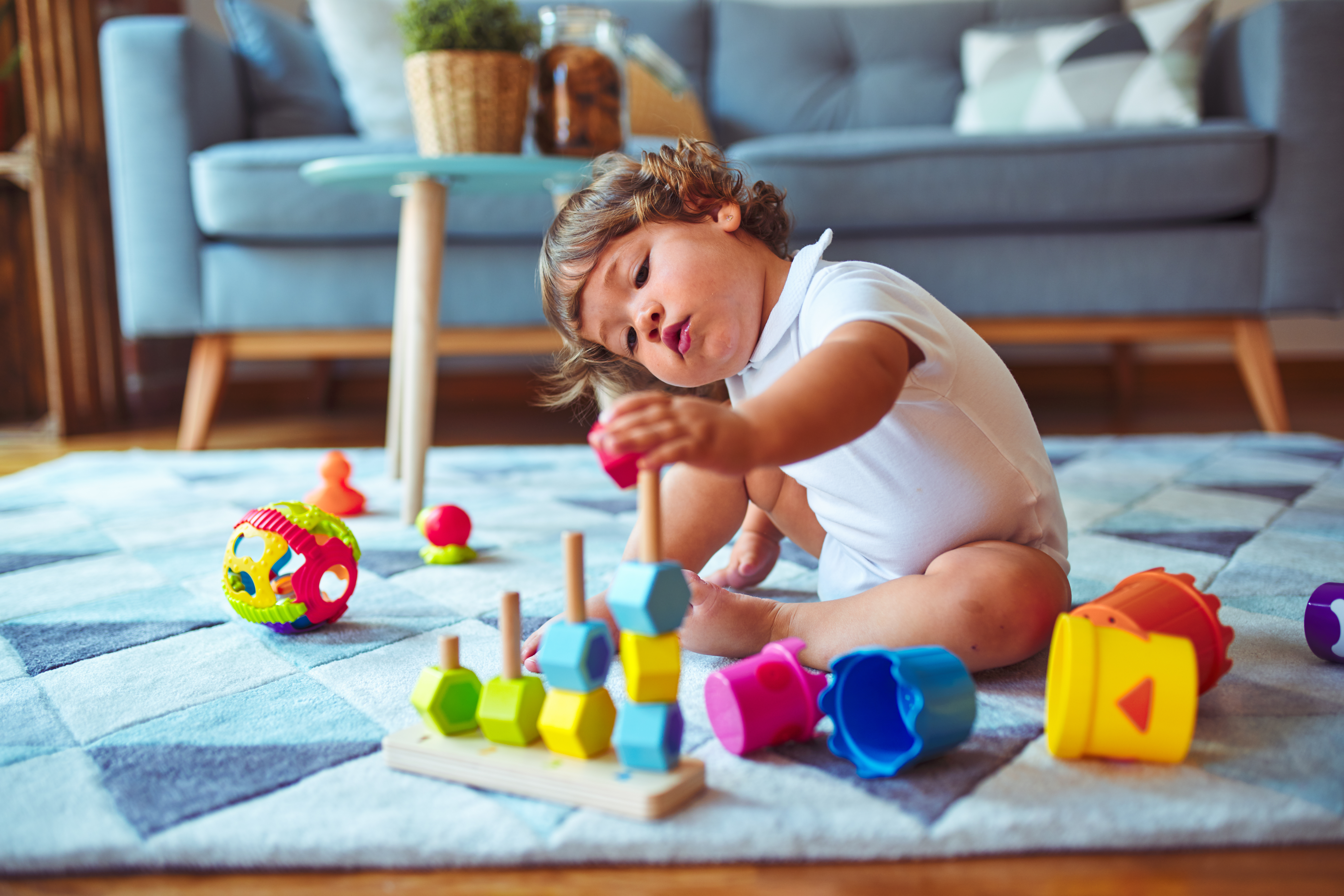 Beautiful toddler child girl playing with toys on the carpet